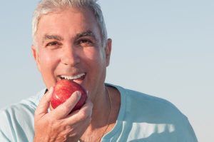 השתלת שיניים גבר אוכל תפוח